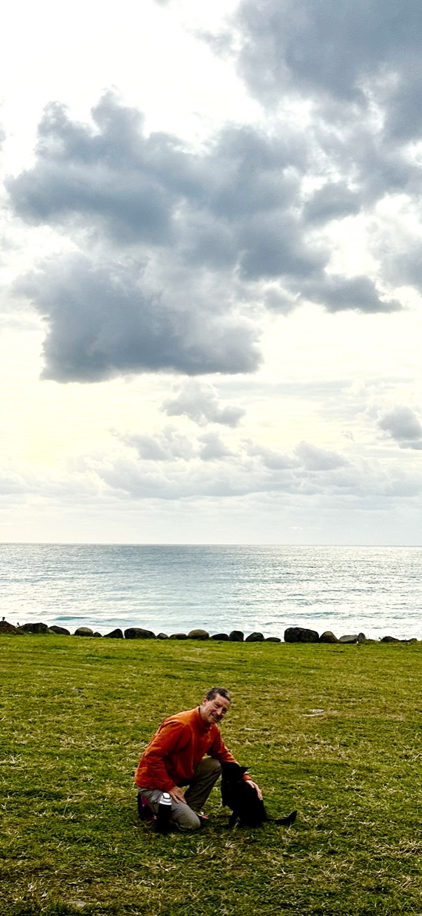 Brent on a grass headland above the Pacific with his dog