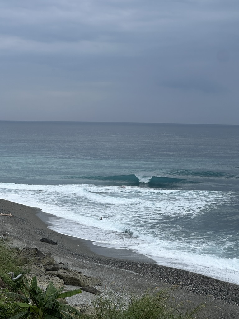 Glassy right-hand peak with a lone surfer paddling