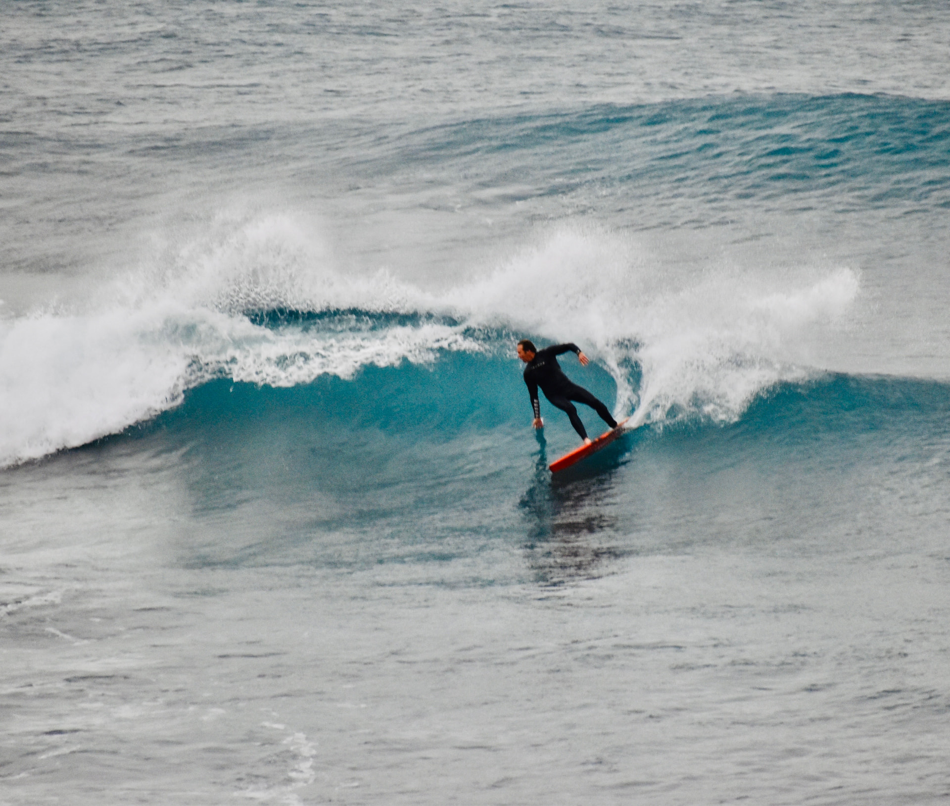 Brent tucking into a clean blue wave on a red board