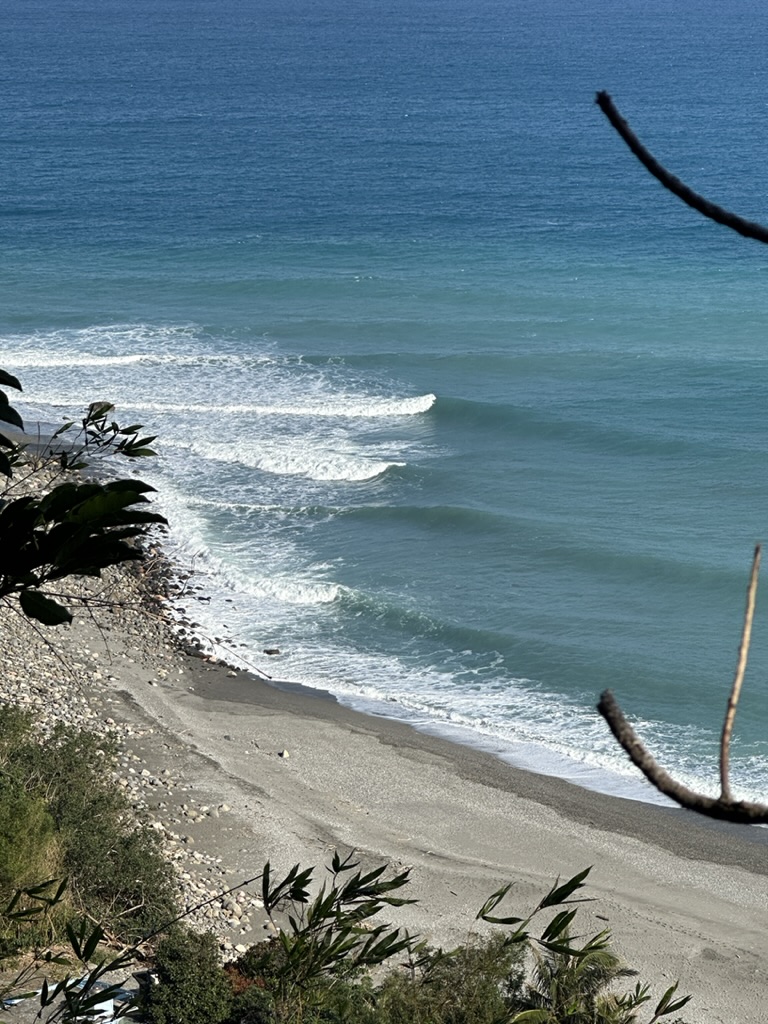 Turquoise lines wrapping onto a pebble beach below a cliff