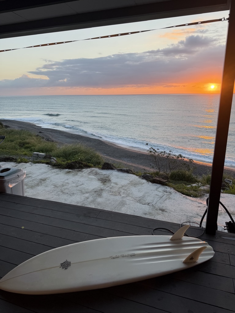 Surfboard on the deck at sunrise, Pacific swell in the distance